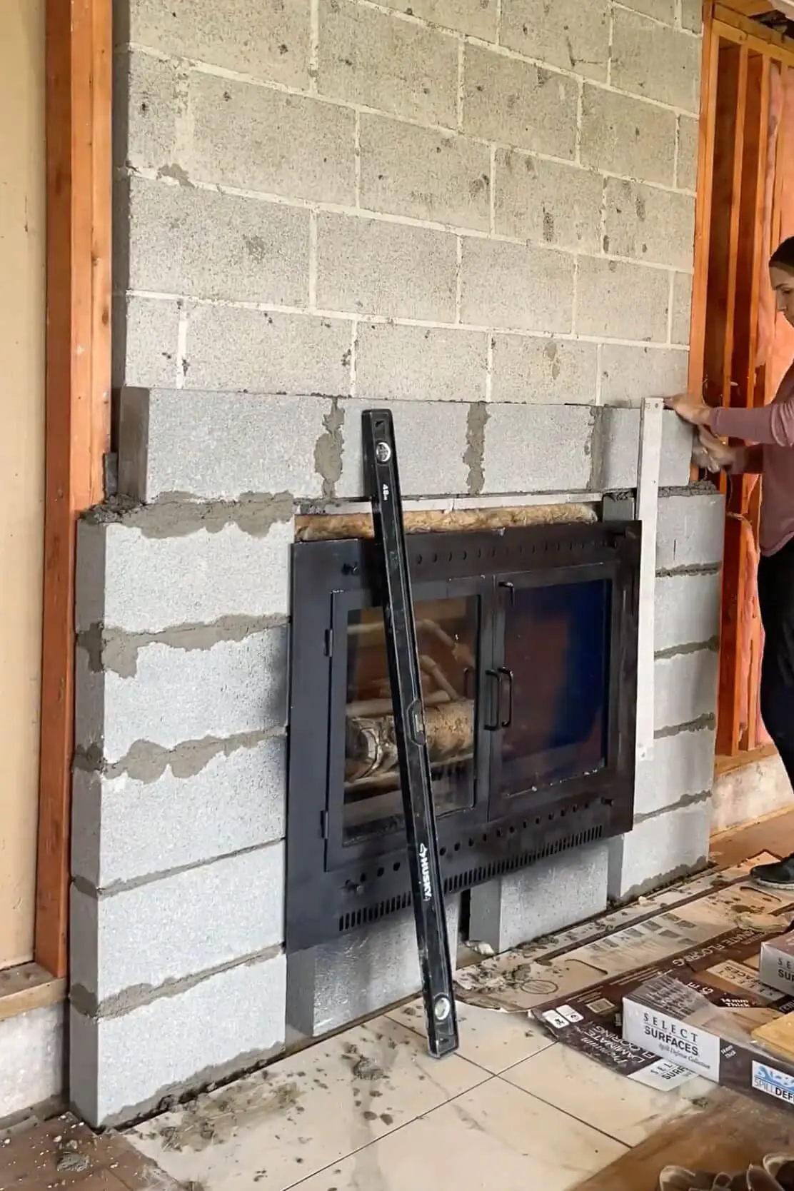 Using mortar to cement in stones on a fireplace surround.